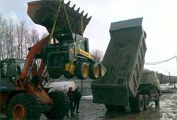 Фронтальный погрузчик Hitachi LX230 грузит мини-погрузчик New Holland L160 в самосвал