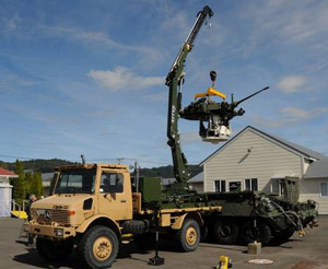 Одна из КМУ Effer 165 на шасси Unimog в процессе подъема башни легкого танка
